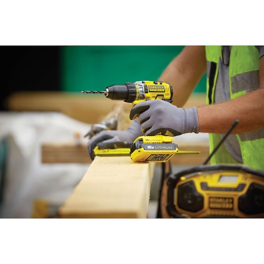 STANLEY FMC600B cordless drill being used on wood, close-up of the tool with yellow and black accents.