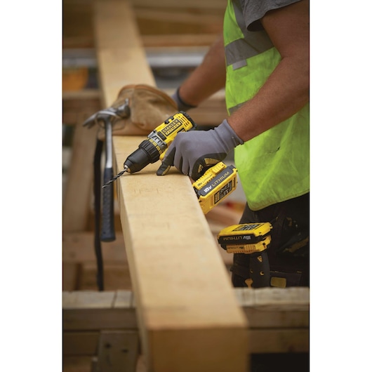 STANLEY FMC600M2S cordless drill used on wood beam by worker in safety vest, side angle.