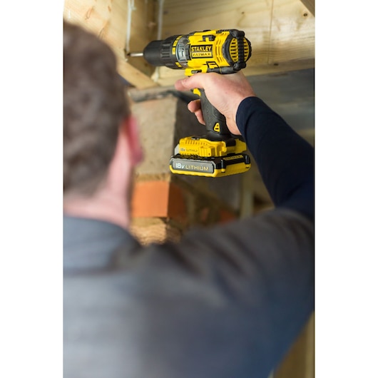 STANLEY FMC625D2 cordless drill with yellow and black design in use, close-up side angle.