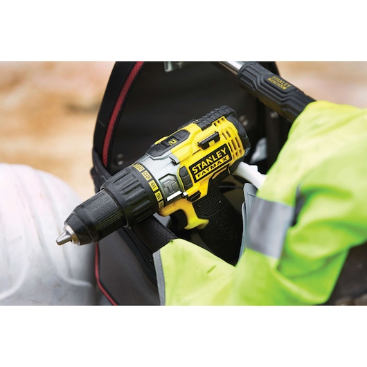 STANLEY FMC625M2S cordless drill, yellow and black, held in a tool bag with a high-visibility jacket.