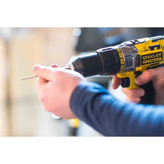 STANLEY FMC625M2S cordless drill held in hand, yellow and black, close-up, in workshop setting.