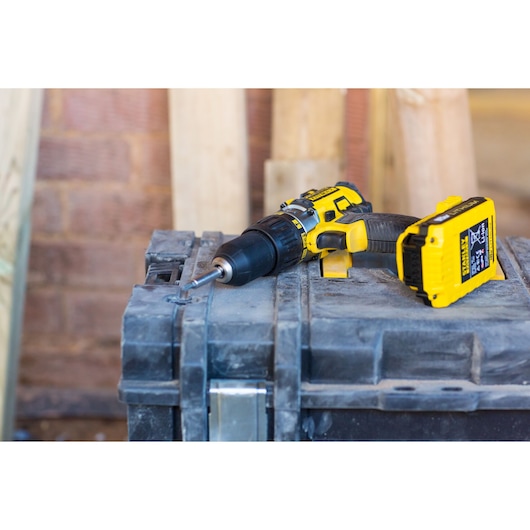 STANLEY FMC625M2S cordless drill with yellow and black design resting on a rugged toolbox, angled side view.