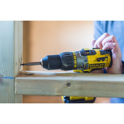 Stanley FMC625M2S cordless drill driver in use, drilling screw into wooden beams, close-up side view.