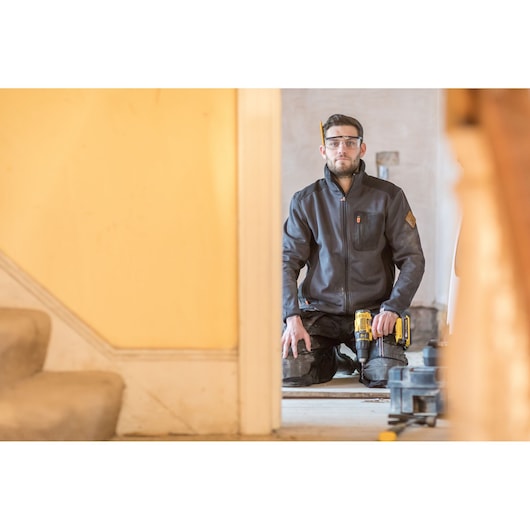 STANLEY FMC626C2K power tool in use by worker kneeling indoors, tool visible in hand, home renovation context.