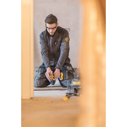 STANLEY FMC647D2 photography of worker kneeling, operating yellow power tool indoors.