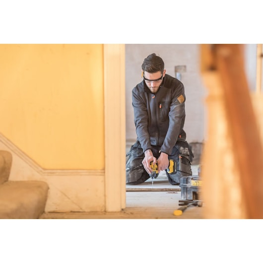 STANLEY FMC647D2 cordless drill in use during indoor renovation, worker kneeling on floor.
