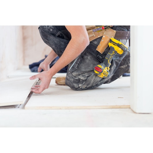 STANLEY FMC647D2 cordless drill attached to tool belt during floor installation, close-up side view.
