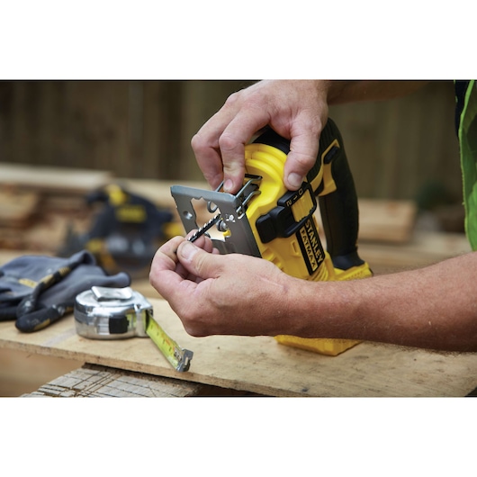 STANLEY FMC650B jigsaw being prepared for use, close-up of hands inserting blade on workbench.