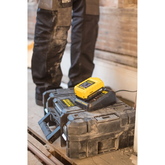 Photo of STANLEY FMC688L battery charger and battery on a rugged toolbox at a construction site.
