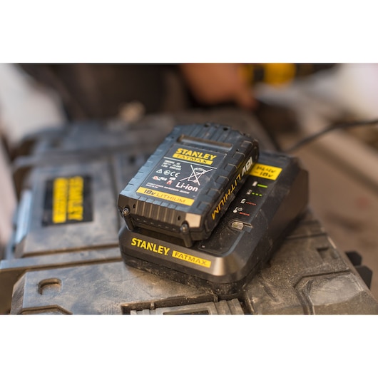 STANLEY FMC692L battery on charger, labeled 18V Li-Ion FATMAX, close-up view in workshop setting.