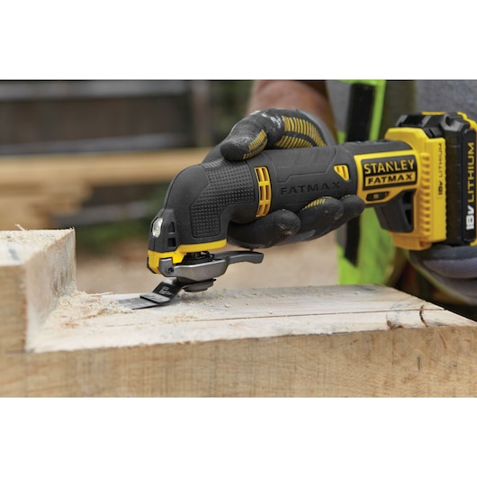 STANLEY FMC710B oscillating tool cutting wood, close-up view, showing FATMAX branding, battery attached.