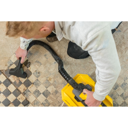 STANLEY FMC795B photography of wet and dry vacuum cleaner in use on dirty tiled floor, top view.