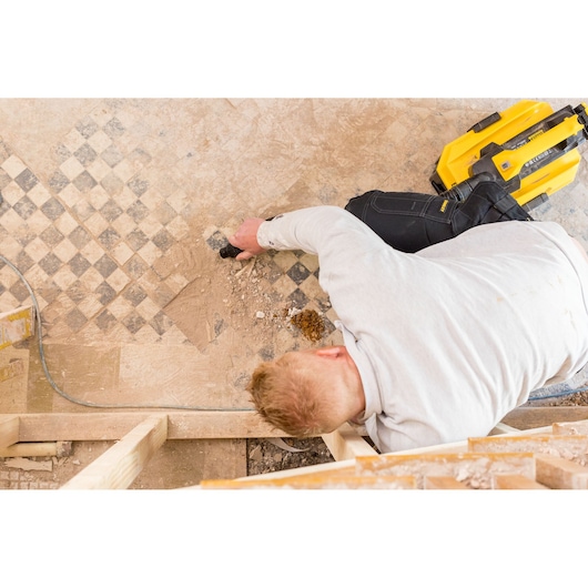 STANLEY FMC795B worker using yellow tool on patterned floor, top view photo of construction scene.