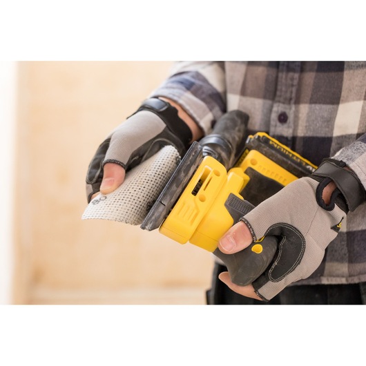 STANLEY FMCW210B sander held by gloved hands close-up, prepping sanding pad, photography.