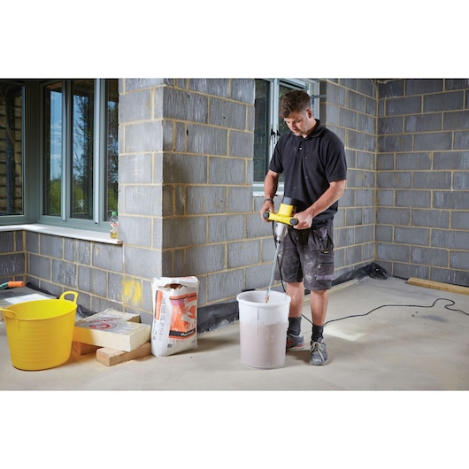 STANLEY FME190-QS paddle mixer used to mix material in a white bucket at a construction site.