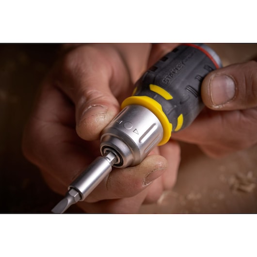 STANLEY FMHT0-62688 screwdriver with yellow and black handle, close-up in use, metal tip visible.