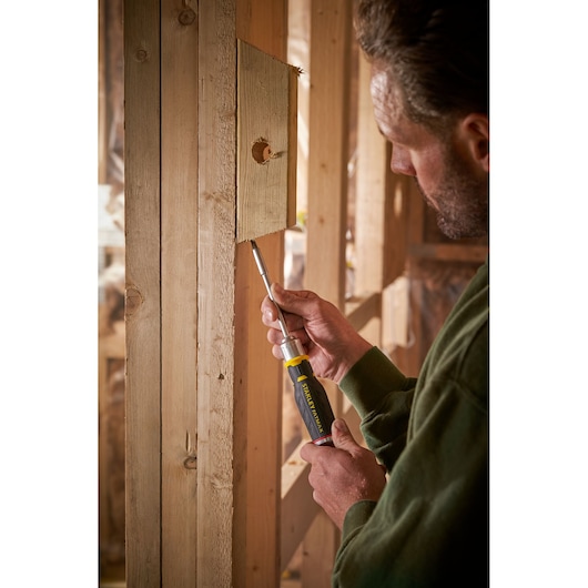Photo of STANLEY FMHT0-62690 screwdriver in use on wooden framing, product held in hand.