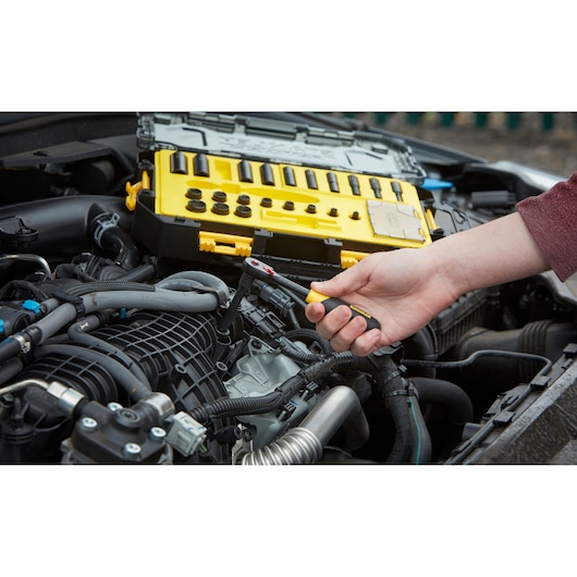 Photo of STANLEY FMHT0-74713 ratchet wrench set used to work on a car engine, yellow tool case visible.