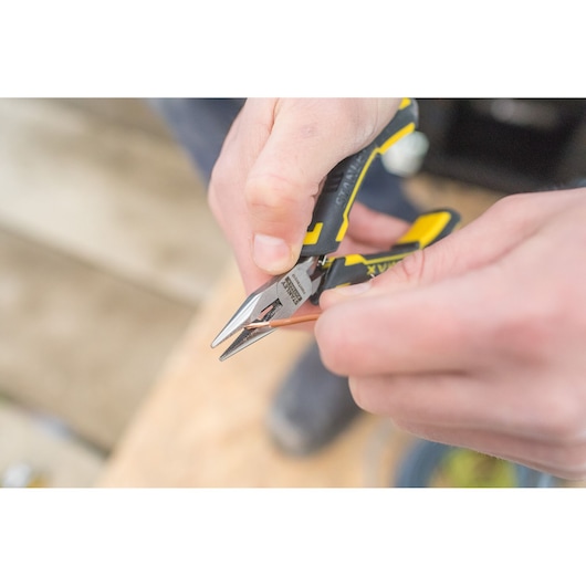 Stanley FMHT0-80517 pliers with yellow and black handle cutting copper wire, close-up photo.