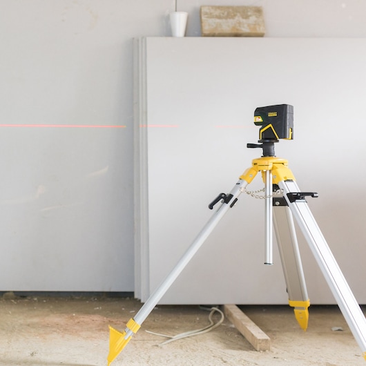 STANLEY FMHT1-77414 laser level on tripod, side angle, showing red laser line, construction photography.