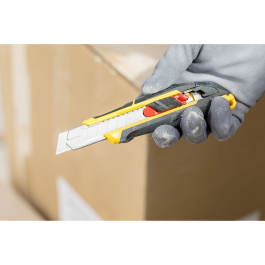STANLEY FMHT10338-0 utility knife with yellow and black handle, photography showing tool held in gloved hand.