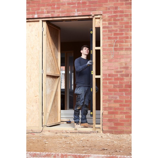 Photo of worker using STANLEY FMHT42561-1 spirit level at door frame construction site.