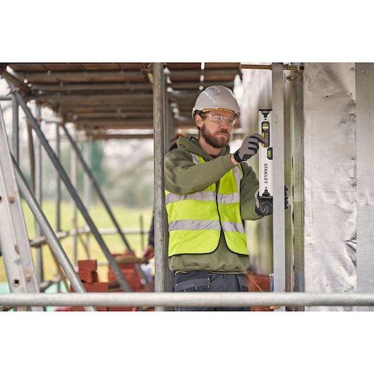 Photo of worker using STANLEY FMHT43671-1 spirit level on construction site, wearing hi-vis vest and helmet.