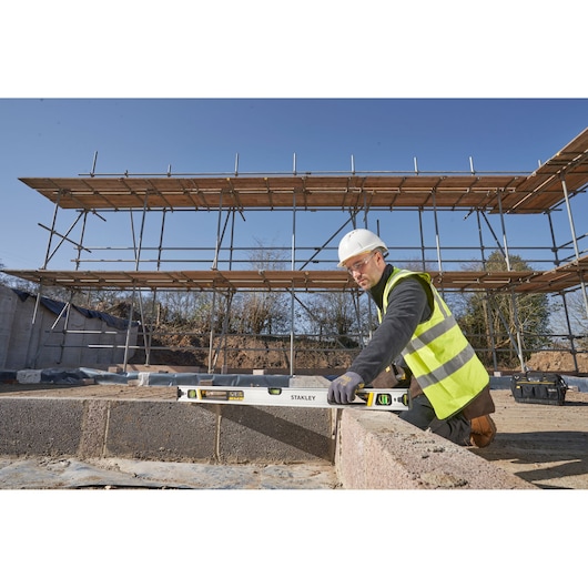 STANLEY FMHT43674-1 spirit level used on a construction site by a worker in high-visibility vest.
