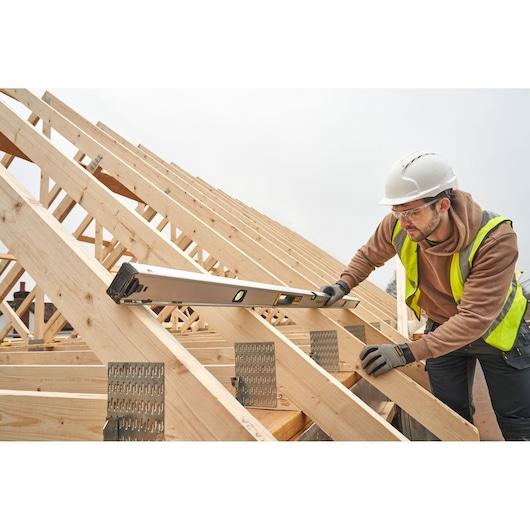 Photo of STANLEY FMHT43680-1 spirit level used on a wooden roof structure during construction.