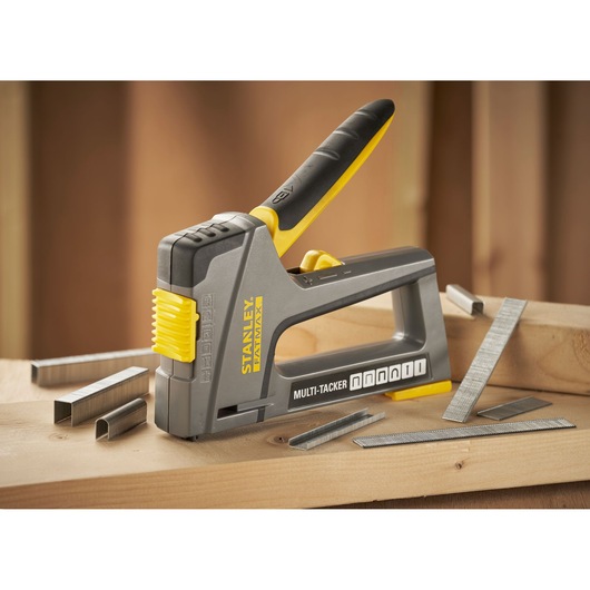 STANLEY FMHT6-70868 Multi-Tacker stapler in grey and yellow with staples on wooden surface.
