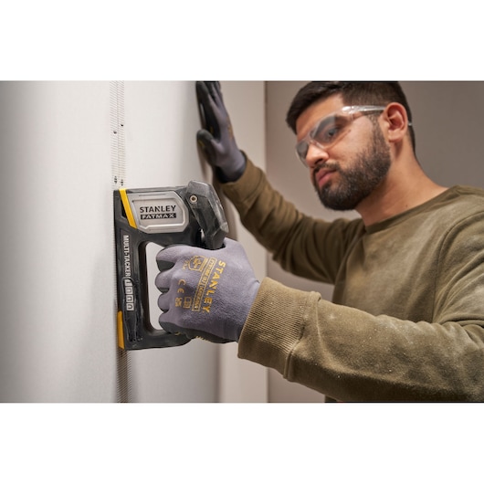 STANLEY FATMAX FMHT70401-0 multitacker used on drywall by person wearing STANLEY gloves, side view.