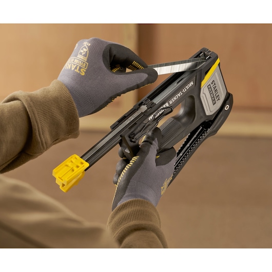 Photo of STANLEY FMHT70401-0 stapler being loaded with staples, shown in hand with gloves.