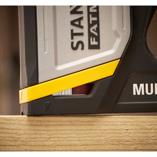 Close-up of STANLEY FMHT70401-0 stapler tool with yellow detail, shown on a wooden surface, side angle.