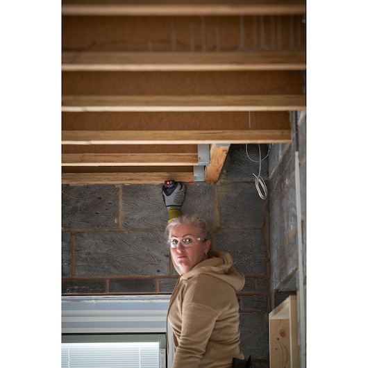 Photo of STANLEY FMHT77165-0 laser measurer in use on wooden ceiling beams in construction setting.