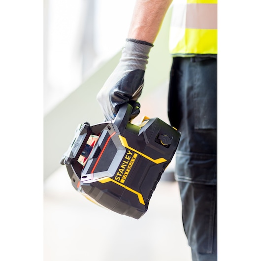 Photo of STANLEY FMHT77447-1 black and yellow handheld device, carried by a gloved hand, close-up view.