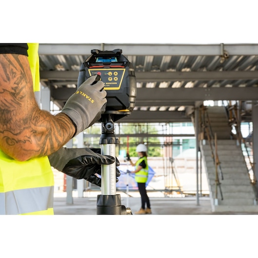 STANLEY FMHT77449-1 rotary laser level on tripod, used at a construction site.
