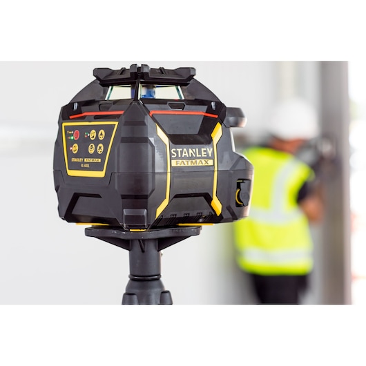 STANLEY FMHT77449-1 rotary laser level on tripod, black and yellow, in construction setting.