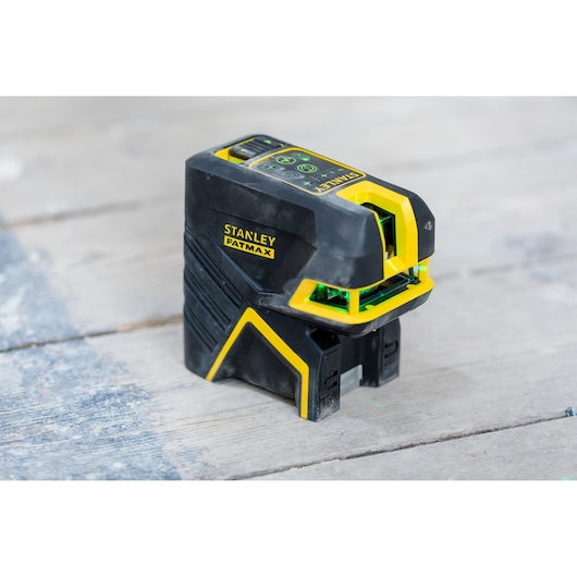 STANLEY FMHT77597-1 laser level, black and yellow, angled view on wood surface.