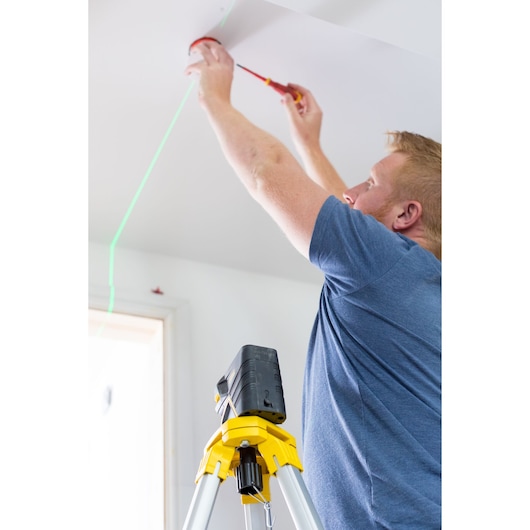 STANLEY FMHT77597-1 laser level on tripod projecting green line for ceiling installation.