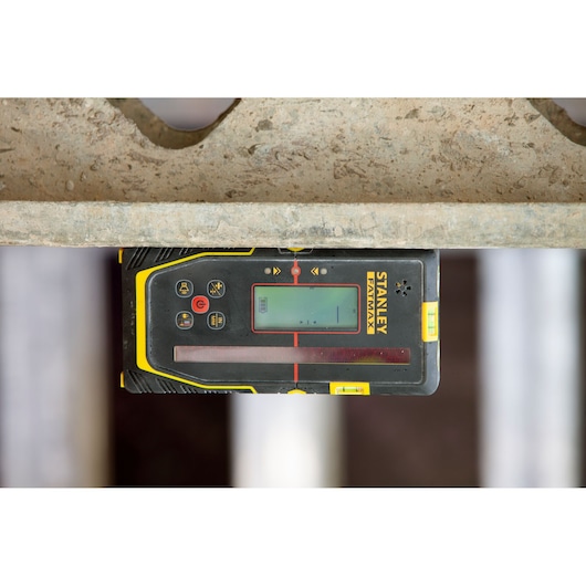 STANLEY FMHT77652-0 laser detector with display, close-up top view, construction context, black and yellow casing.