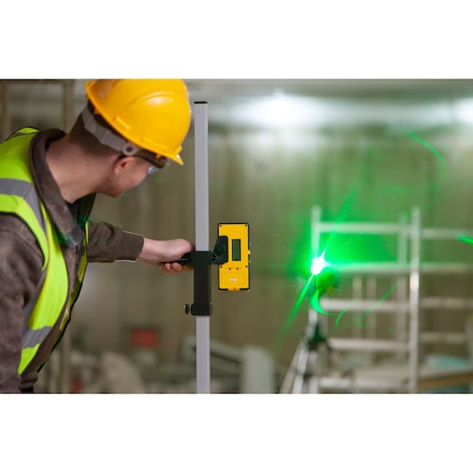 STANLEY FMHT77653-0 laser detector held by worker near green laser beam, construction setting.