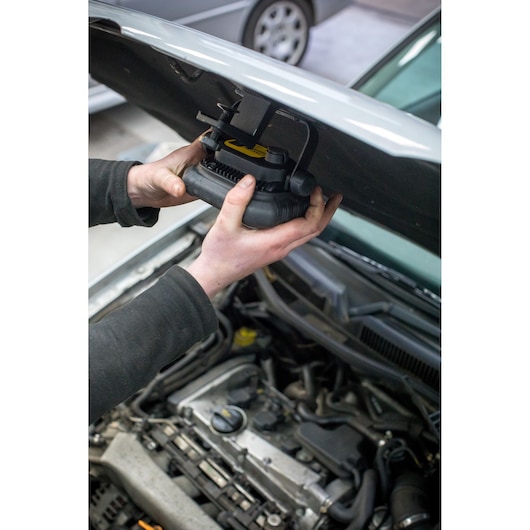 Photo of a person attaching a STANLEY FMHT81507-1 work light under a car hood, focusing on the installation process.