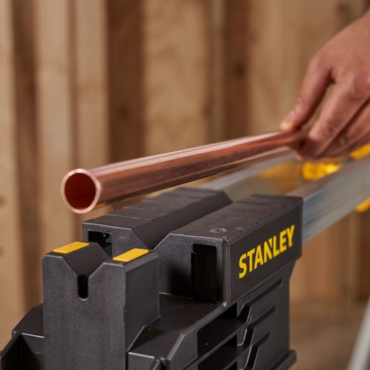 Photo of STANLEY FMST1-75763 workbench holding a copper pipe, close-up angle.