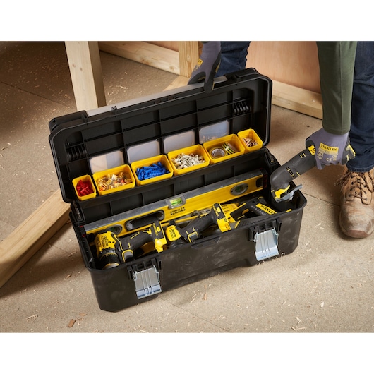 STANLEY FMST1-75791 toolbox with yellow compartments and power tools, top view on workshop floor.