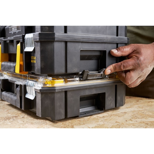 STANLEY FMST82967-1 modular black plastic toolbox stack, close-up of latch being operated by hand.