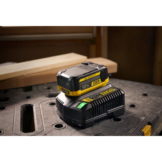STANLEY SFMCB204 battery and charger, black and yellow, on workshop table, product photography.