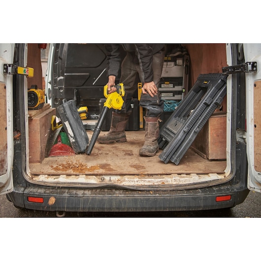 STANLEY SFMCBL01B blower clearing debris from van floor during worksite cleanup.