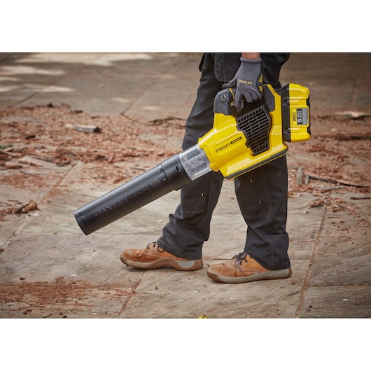 Photo of STANLEY SFMCBLB76B cordless leaf blower in use, yellow and black design, outdoor setting.