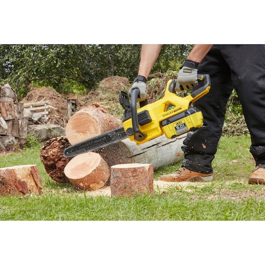STANLEY SFMCCSB664B chainsaw cutting logs outdoors, showing yellow body and black blade.