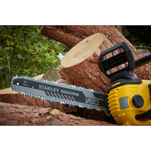 Photo of STANLEY SFMCCSB664B chainsaw cutting logs; yellow body, 16in 40cm blade, outdoor setting.